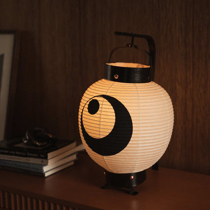 Kleine gloeiende Japanse papieren lantaarn met zwart maanontwerp op een houten oppervlak met warme washipapiertextuur
