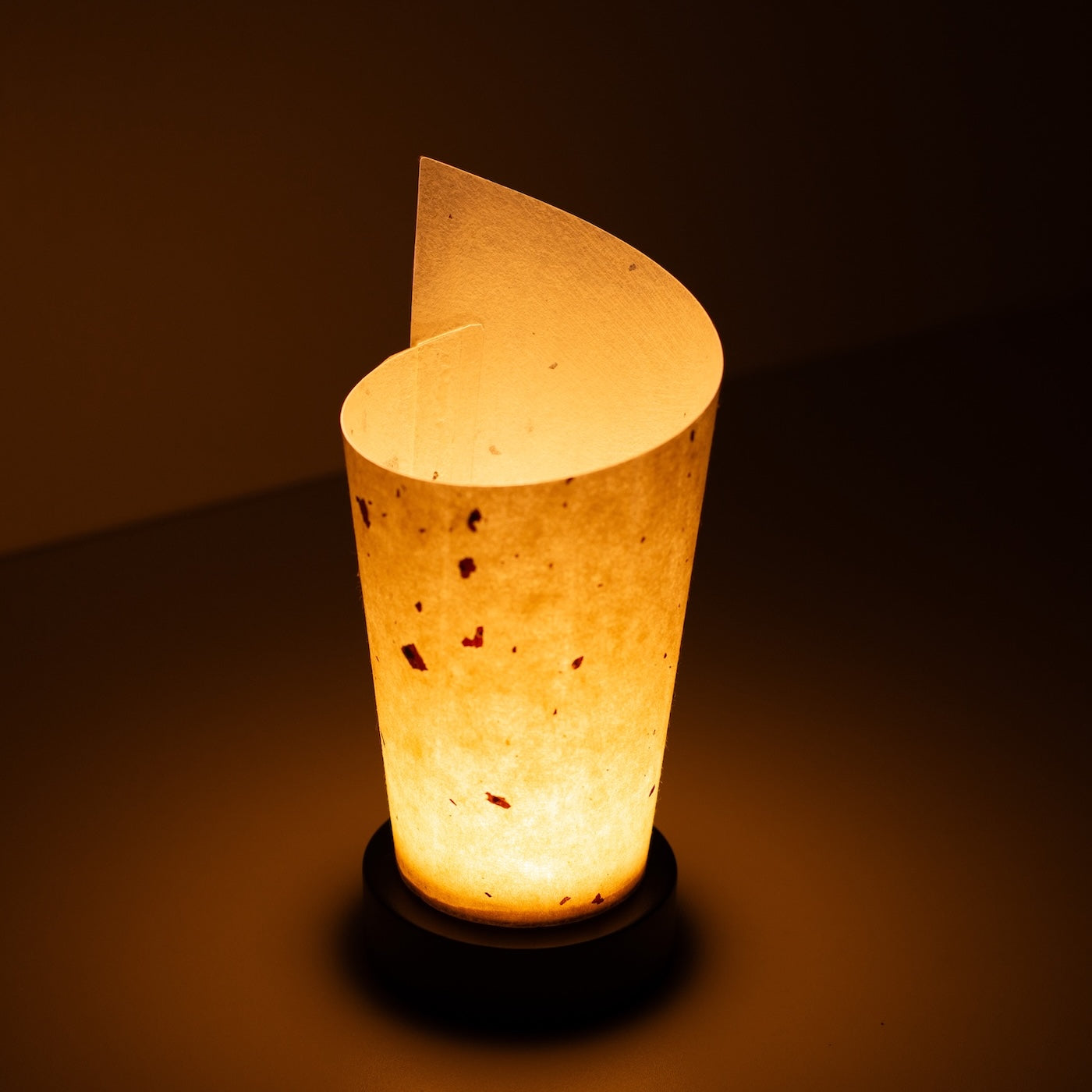 "Lampe de table japonaise en papier « Maki », naturel, papier Mino Washi - vue en plongée d'une lampe Japandi allumée montrant son design enroulé."