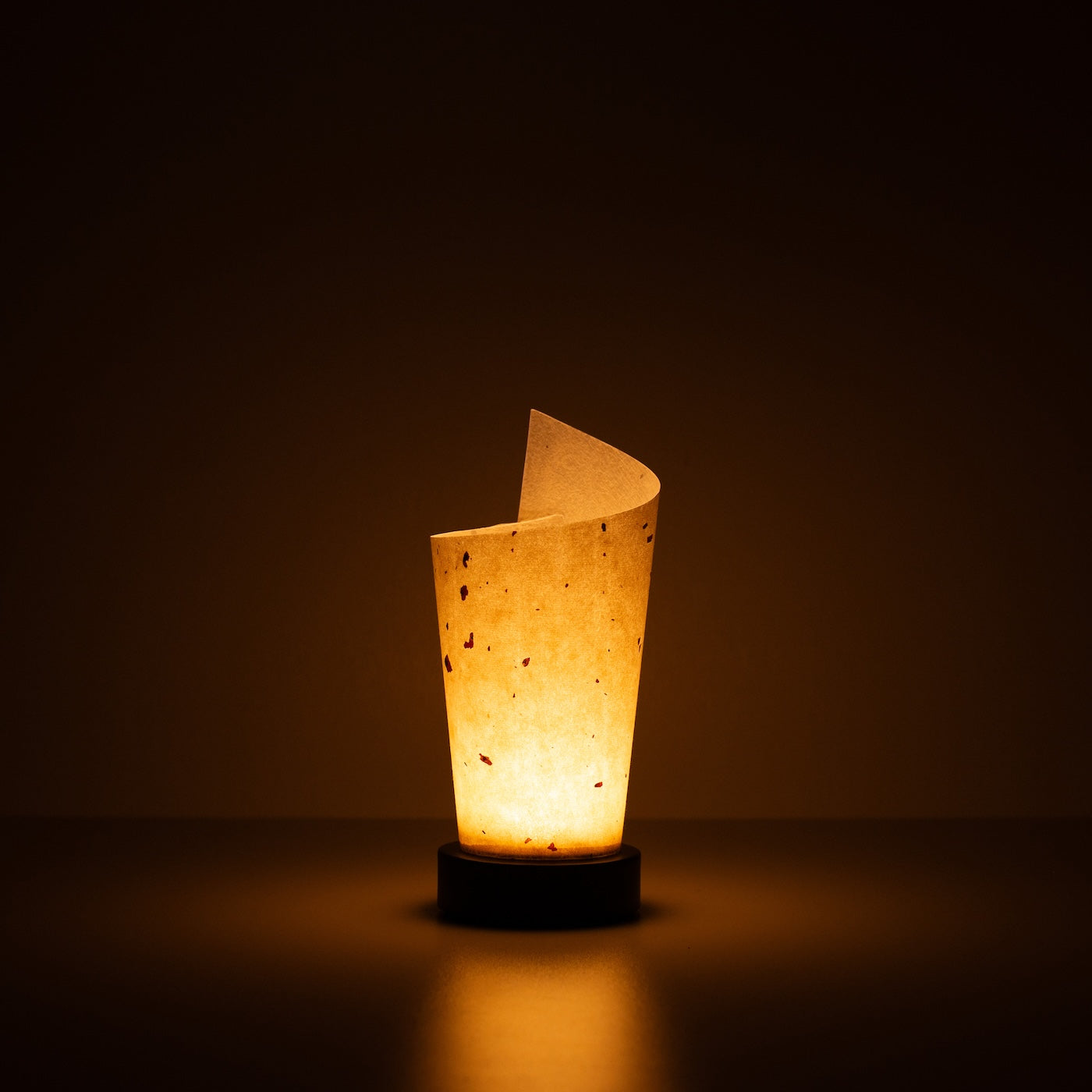 "Lampe de table japonaise en papier « Maki », naturelle, papier Mino Washi - lampe en papier allumée projetant une lueur chaleureuse avec des marbrures rustiques visibles."