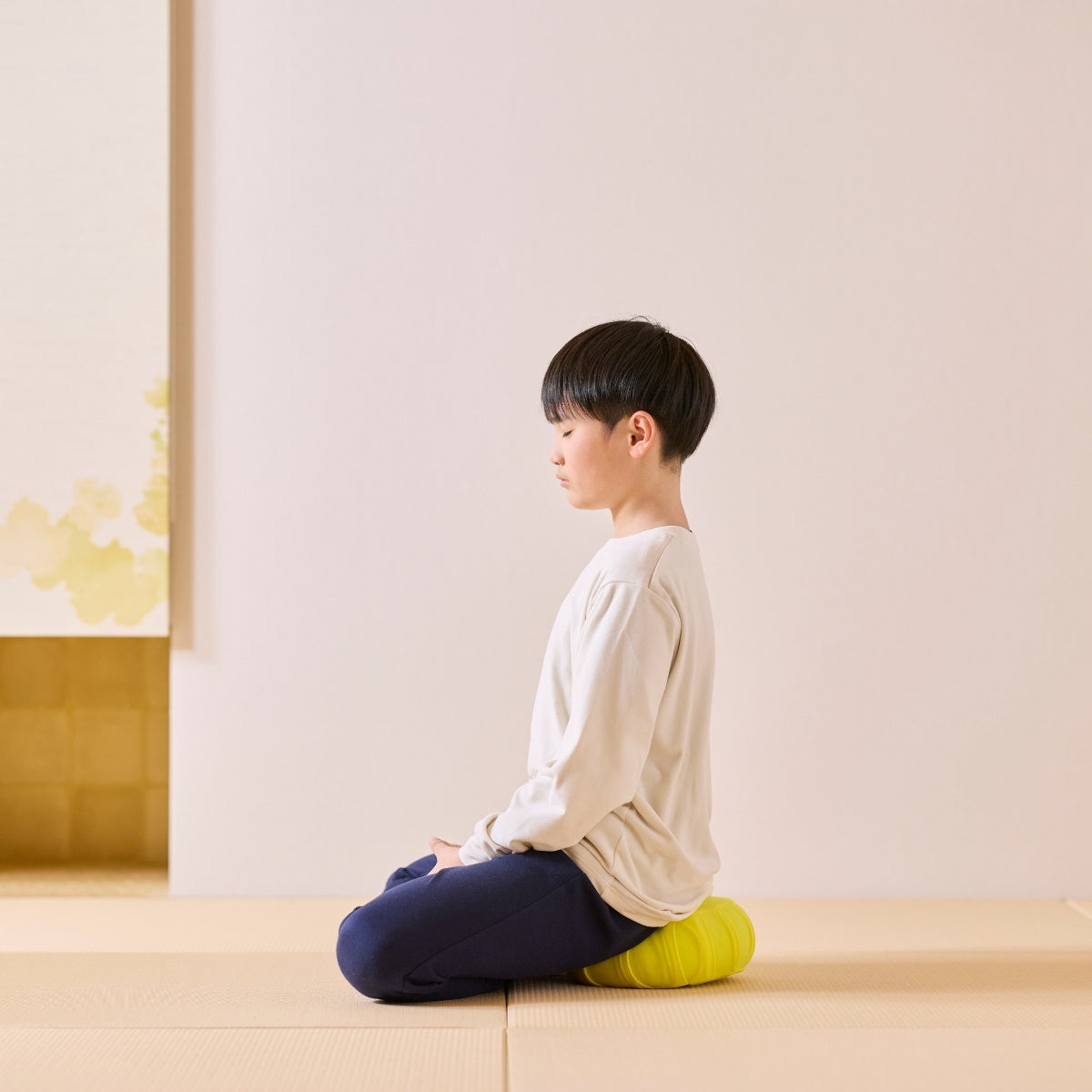 Mimosa gul japansk meditationspude zafu, brugt af et barn på en tatami-måtte, der praktiserer en daglig mindfulness-rutine.