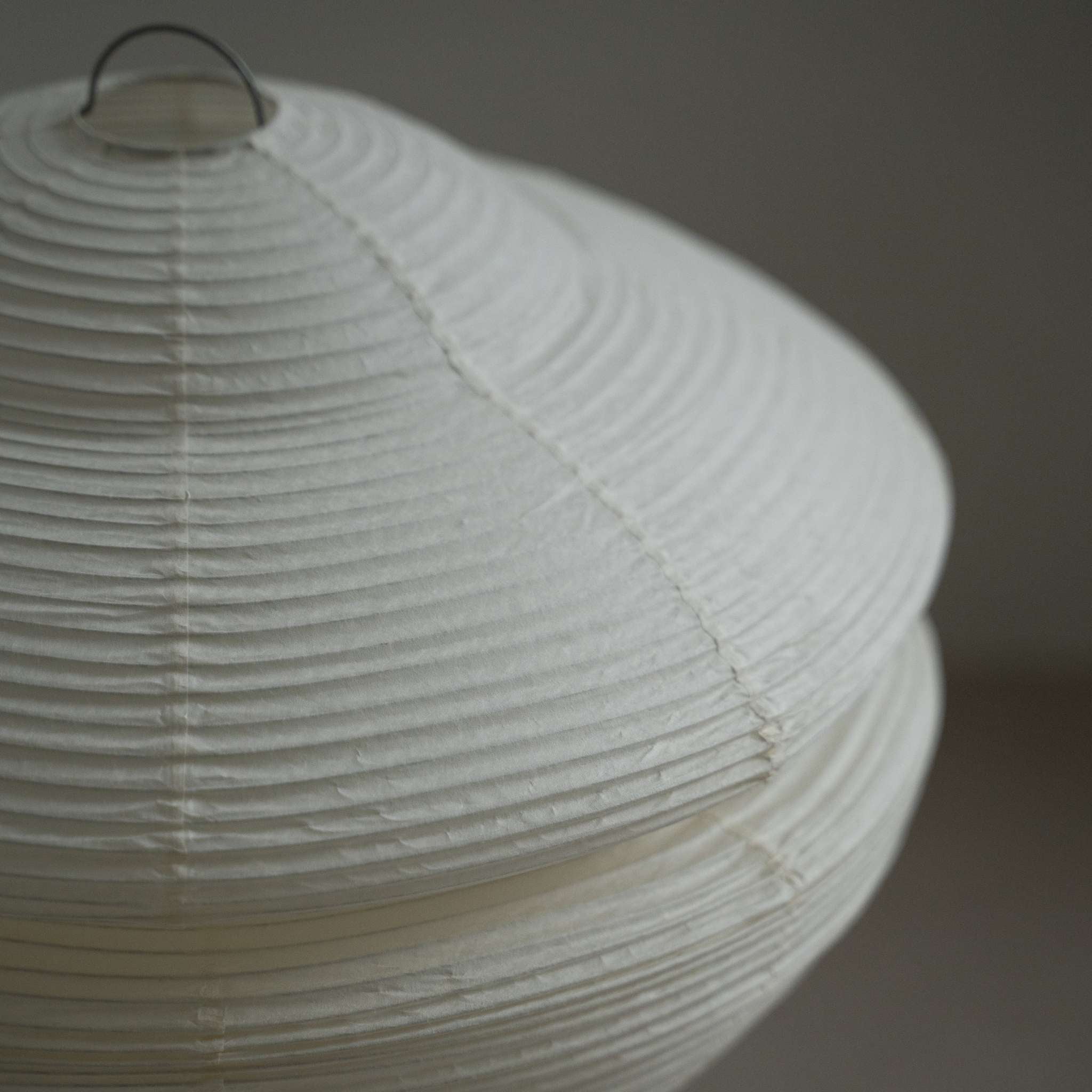 Gros plan montrant la texture translucide et le design côtelé du papier Harusame Mino Washi sur l'abat-jour Gemini 01.