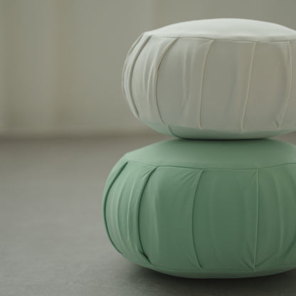 Coussin de méditation zafu japonais blanc clair de lune et vert menthe, empilé dans une pièce moderne, prêt pour une routine zen familiale.