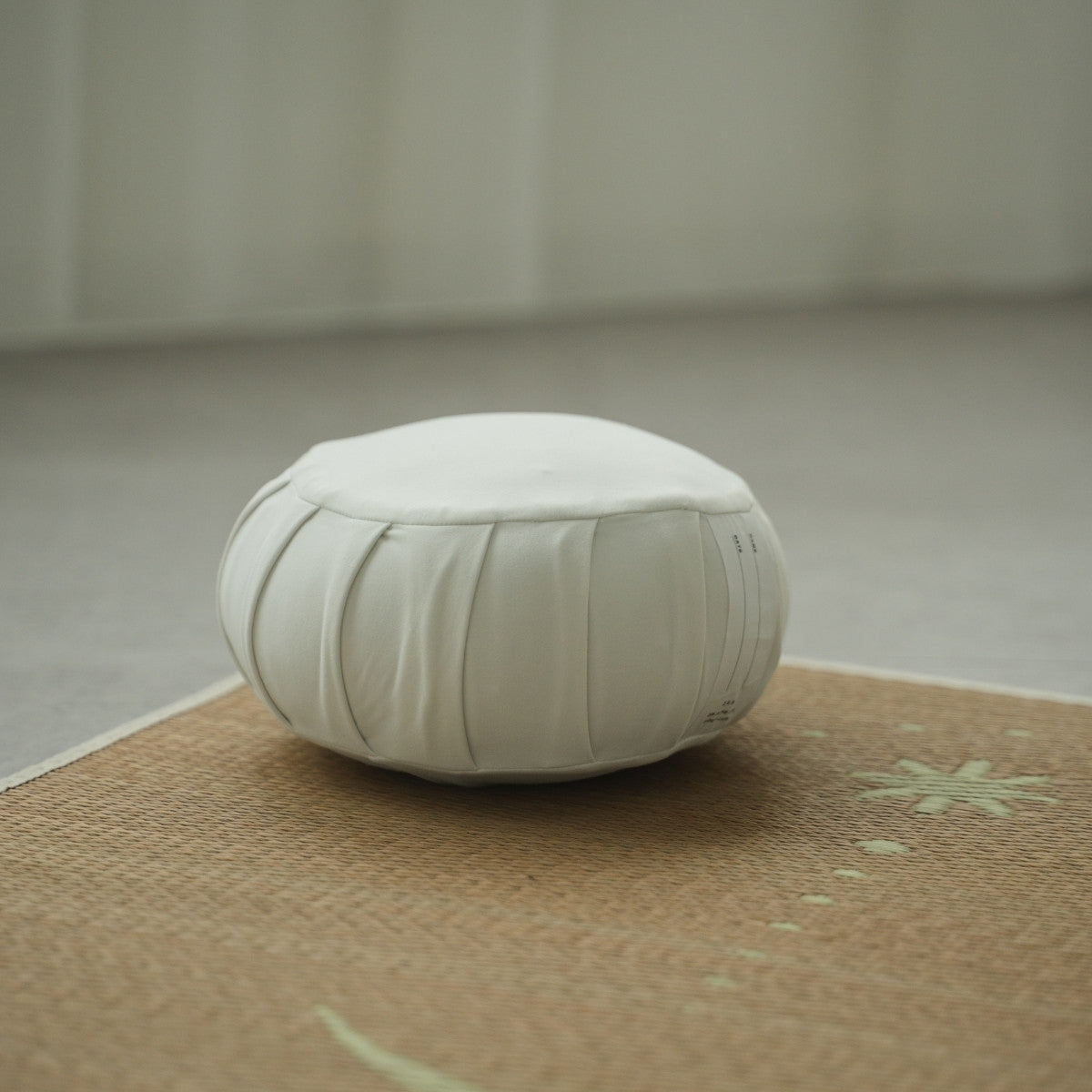 Coussin de méditation zafu japonais blanc clair de lune, sur un tapis tatami dans une pièce lumineuse pour une routine zen matinale.