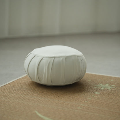 Coussin de méditation zafu japonais blanc clair de lune, sur un tapis tatami dans une pièce lumineuse pour une routine zen matinale.