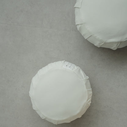Deux coussins de méditation japonais blancs clair de lune (zafu) sur un sol gris moderne, prêts pour une routine de pleine conscience familiale.