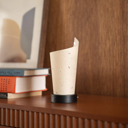 Gros plan d'une lampe de table japonaise en papier non allumée "Maki", mettant en valeur ses marbrures naturelles et son esthétique wabi-sabi sur une console.