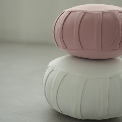 Rose og måneskin hvid japansk meditationspude zafu, placeret på et gråt gulv klar til en familie zen-rutine.