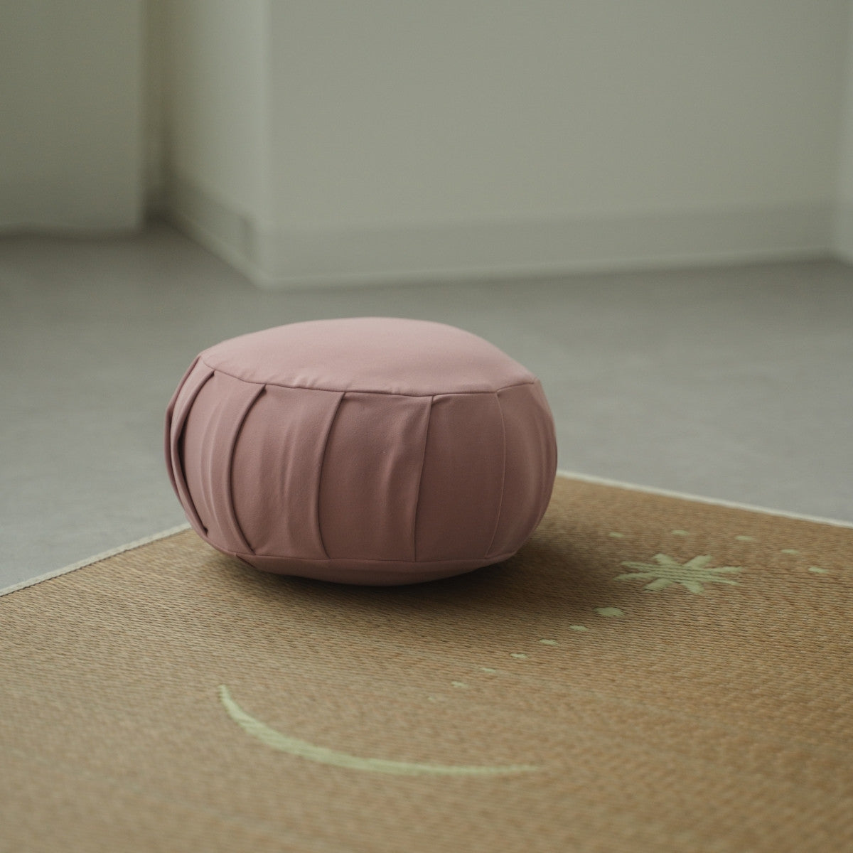Rose japansk meditationspude zafu, placeret på en tatami-måtte i et Japandi-stilrum til en daglig zen-rutine.