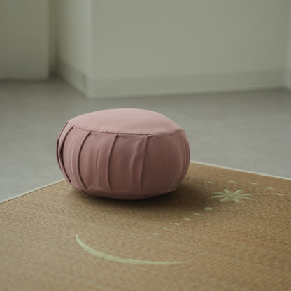 Rose japansk meditationspude zafu, placeret på en tatami-måtte i et Japandi-stilrum til en daglig zen-rutine.