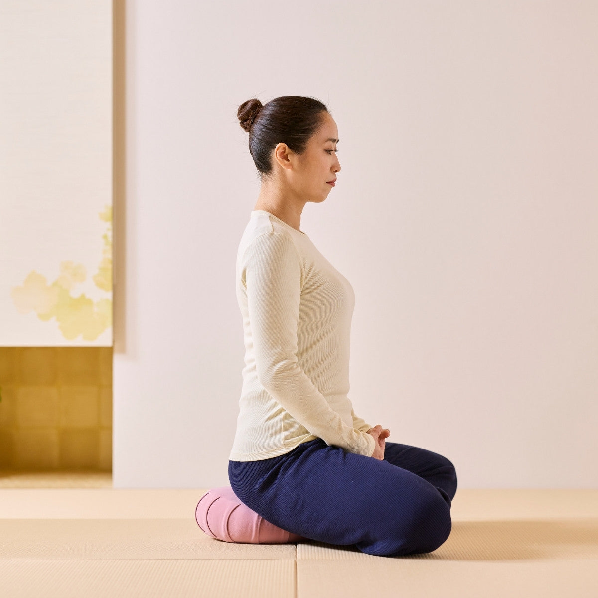 Rose japansk meditationspude zafu, brugt af en kvinde på en tatami-måtte, der praktiserer en rolig morgen zen-meditation.