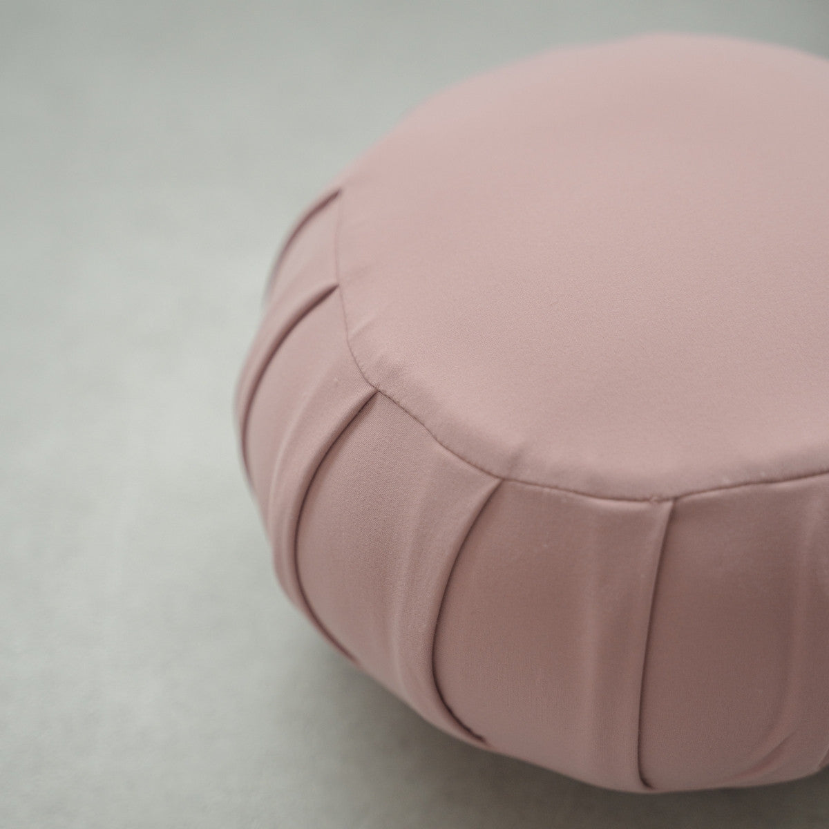 Tæt på en rosefarvet japansk meditationspude (zafu), der viser stoft detaljer på et moderne gulv til afslappende hjemmeyoga.