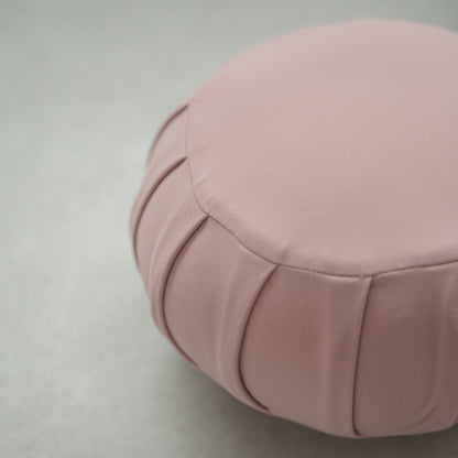 Tæt på en rosefarvet japansk meditationspude (zafu), der viser stoft detaljer på et moderne gulv til afslappende hjemmeyoga.