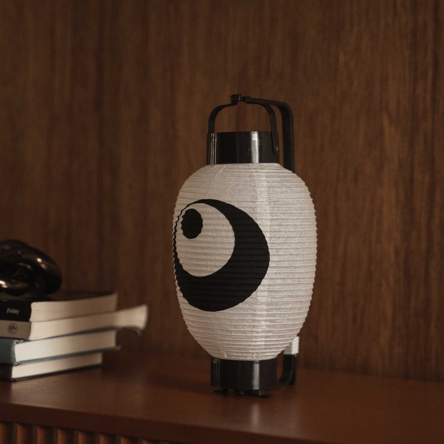 Japanse papieren lantaarn chochin op een donkere houten tafel met het traditionele zwart-inktontwerp.