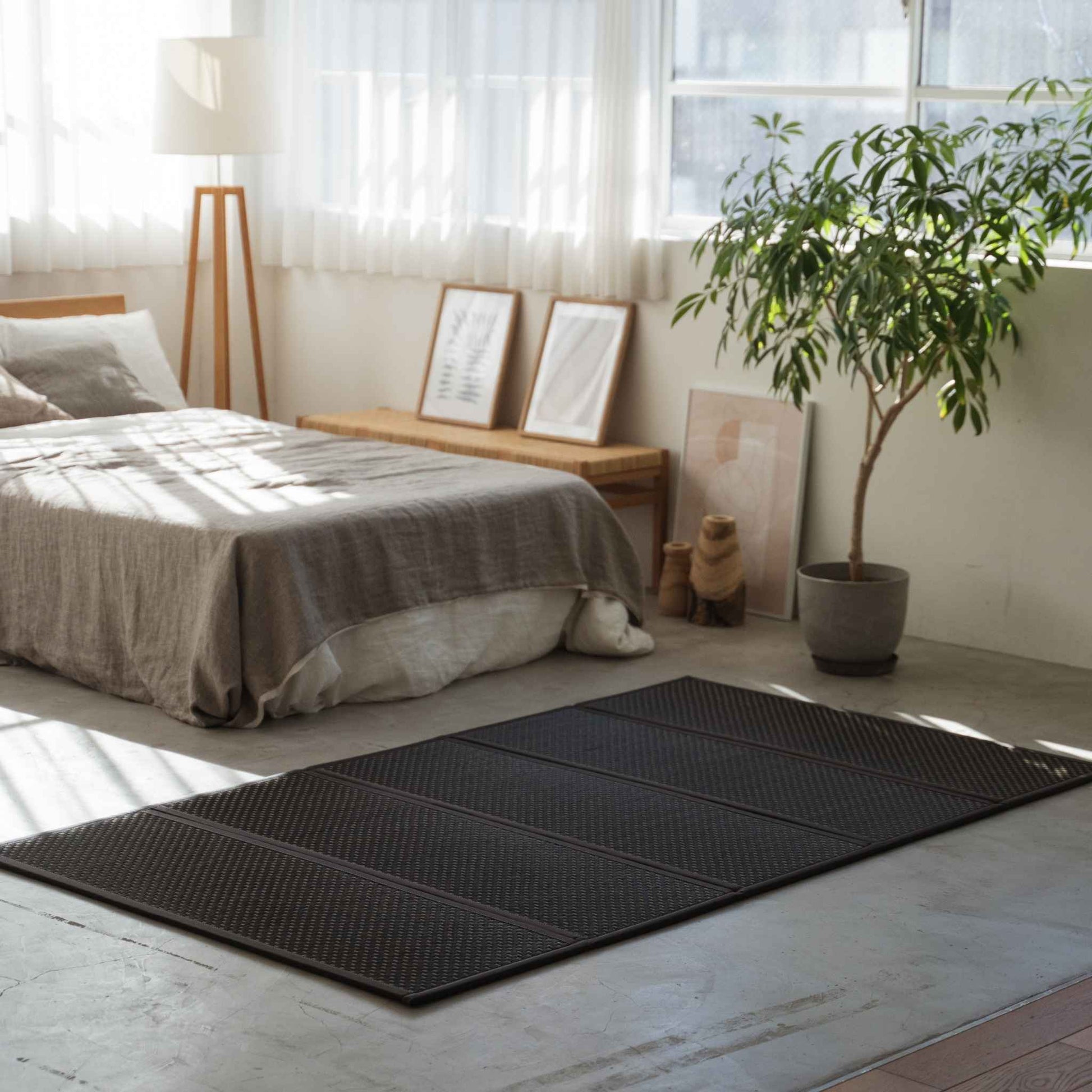 Sort semidobbelt tatamimåtte på et betongulv i soveværelset, der giver et moderne zen-fundament for en futon.