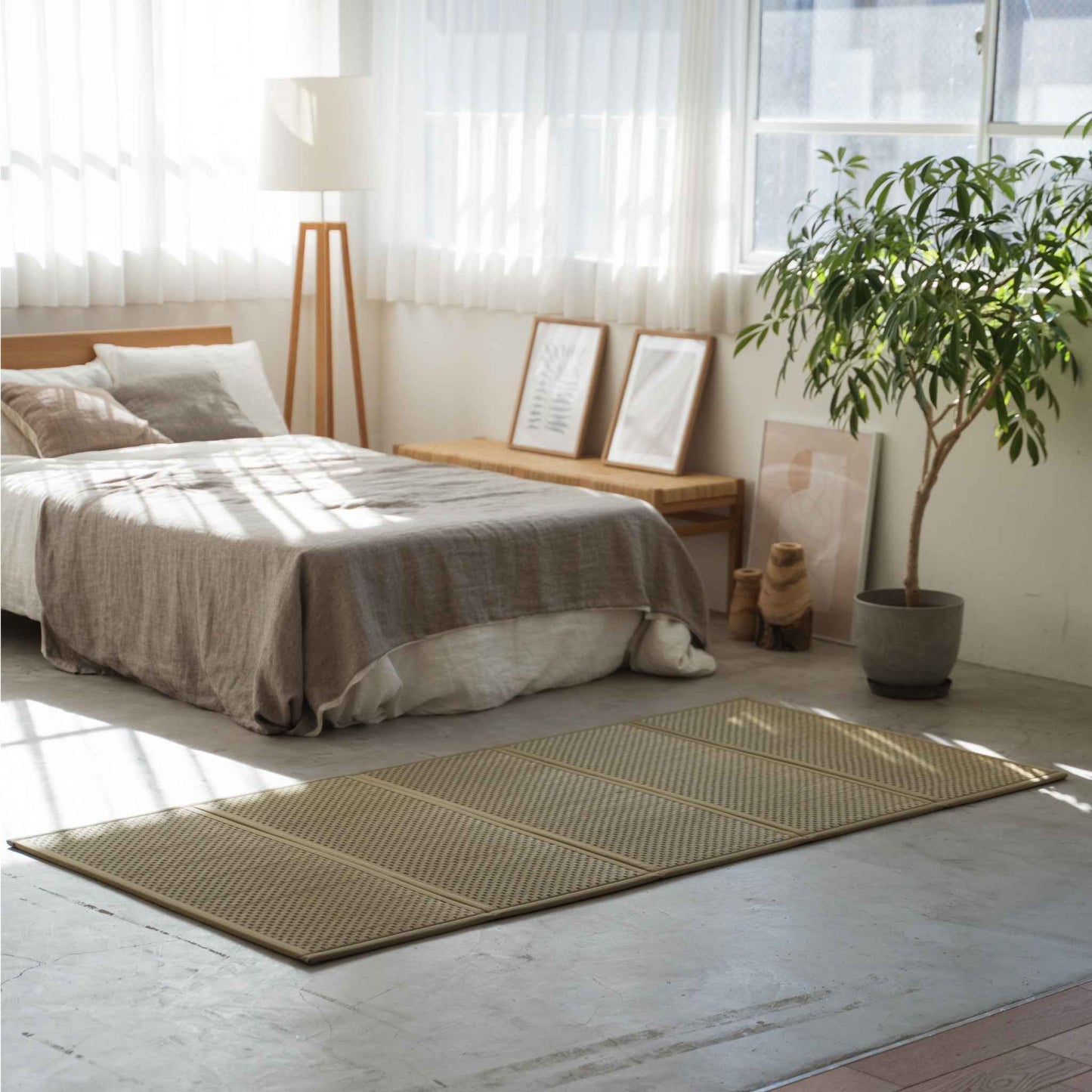 Enkel grøn tatami-madras lagt på et betongulv i soveværelset, der tilbyder en åndbar base til zen-indretning.
