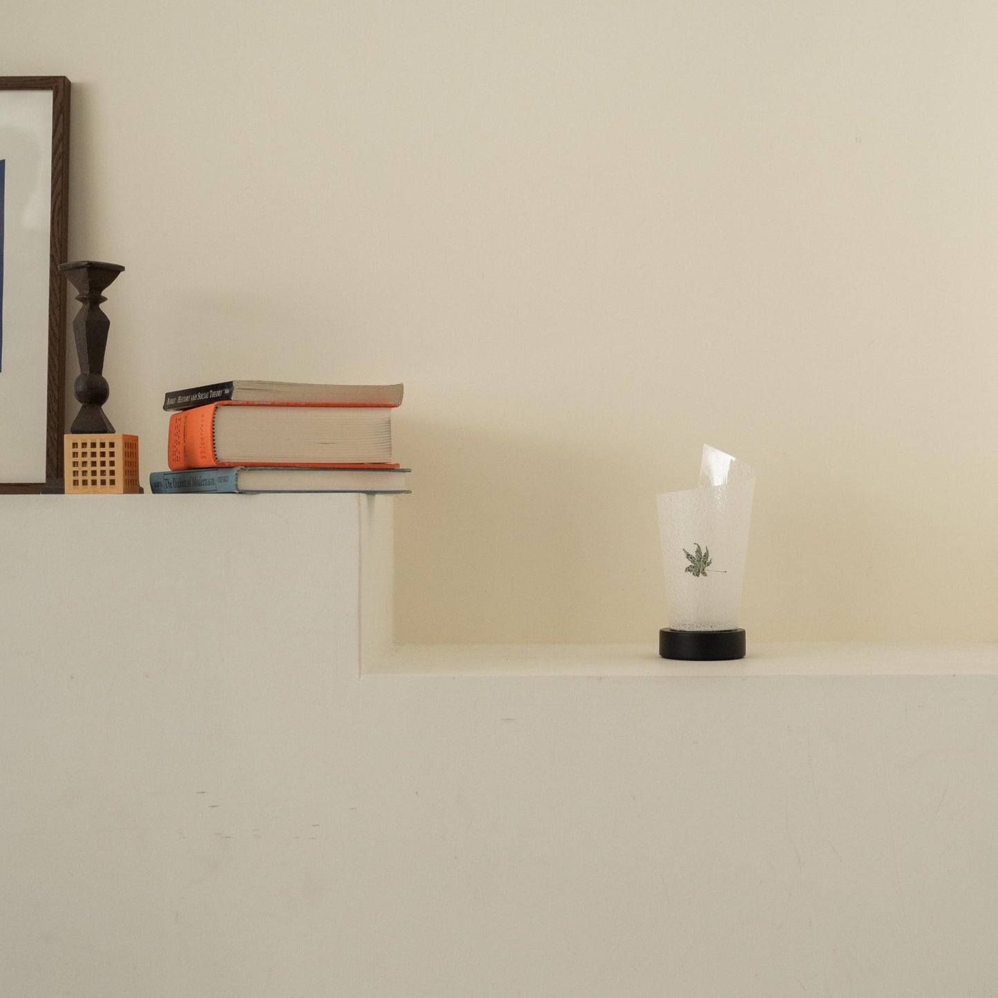 Lampe de table japonaise non allumée en papier "Maki" Feuille Momiji avec des marbrures rustiques sur une console blanche dans un salon Japandi.