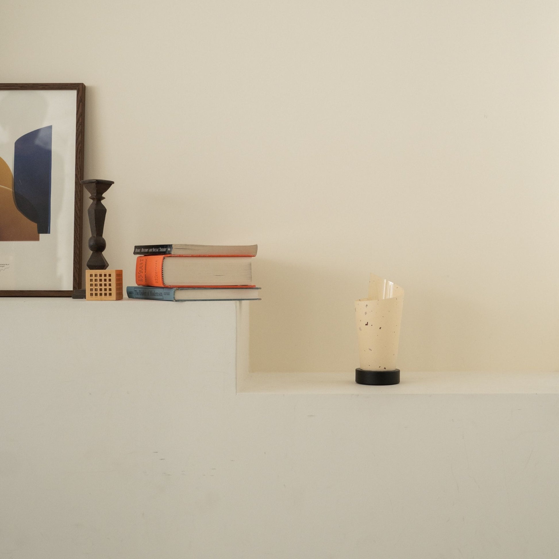 Lampe de table japonaise non allumée en papier "Maki" avec des mouchetures rustiques sur une console blanche dans un salon Japandi.