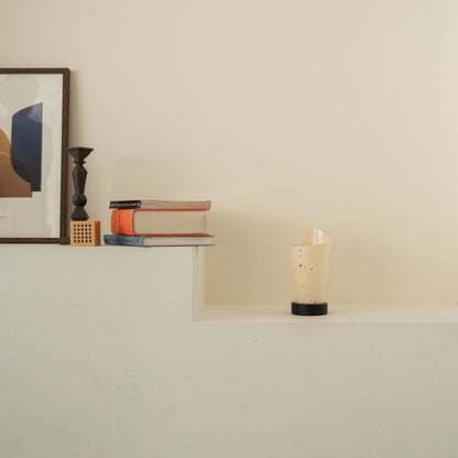Lampe de table japonaise non allumée en papier "Maki" avec des mouchetures rustiques sur une console blanche dans un salon Japandi.