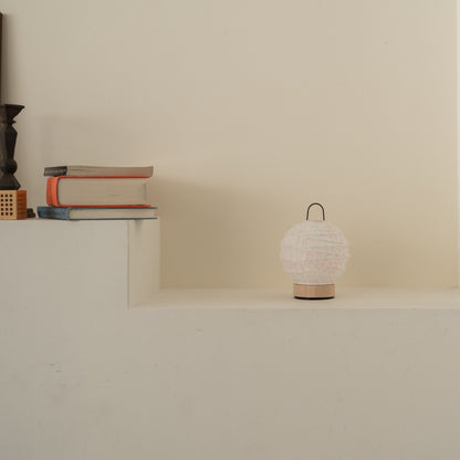 Unlit round Japanese paper table lamp "Yuhi" Sakura placed on a white console table in a minimalist Japandi living room.