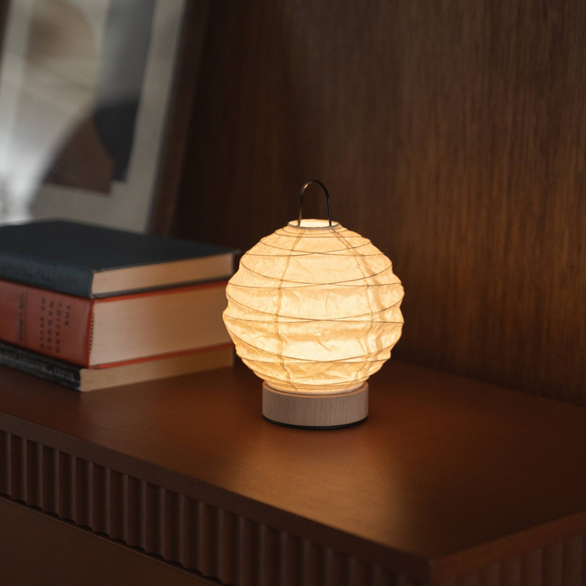 Japanese paper table lamp "Yuhi" emitting a warm glow on a mid-century modern console table.