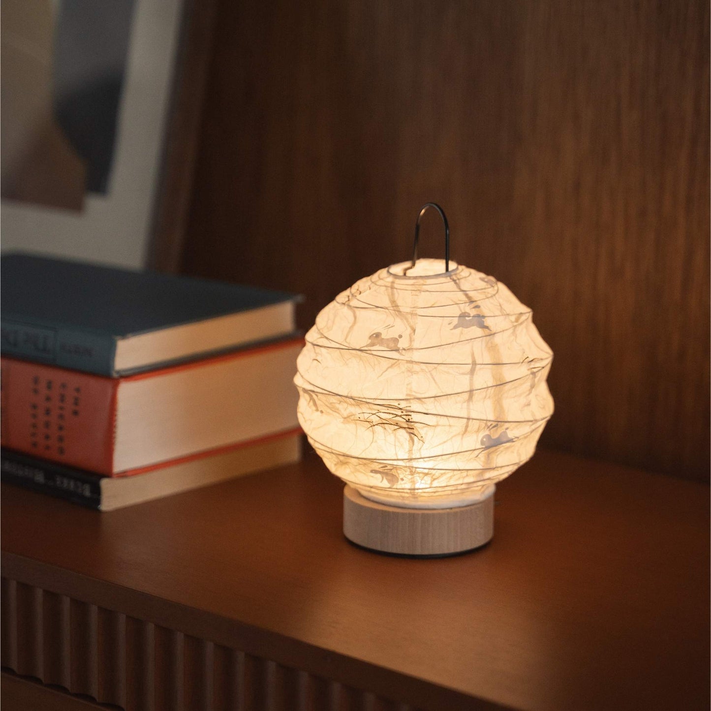 Japanese paper table lamp "Yuhi" emitting a warm glow on a mid-century modern console table.