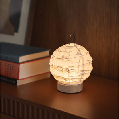 Japanese paper table lamp "Yuhi" emitting a warm glow on a mid-century modern console table.