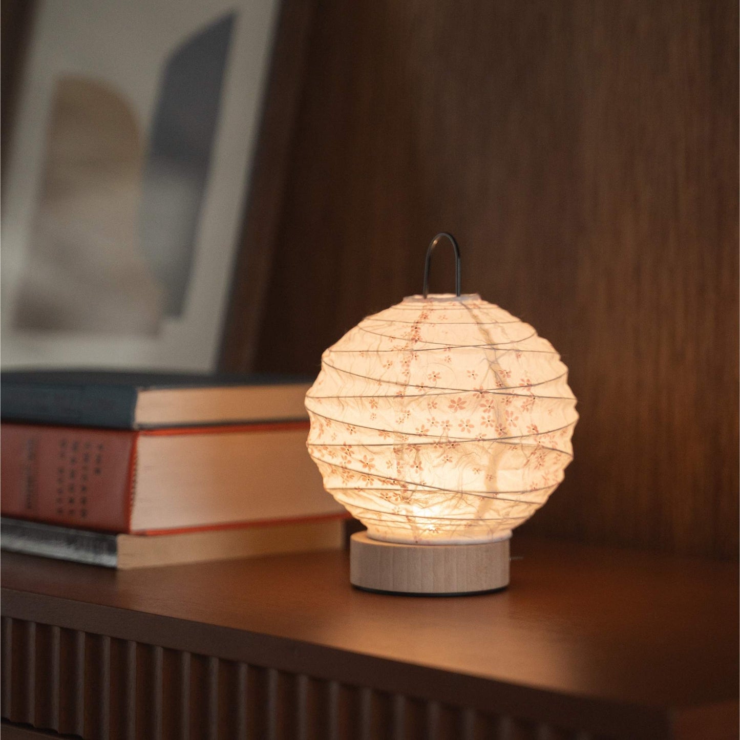 Japanese paper table lamp "Yuhi" Sakura emitting a warm glow on a mid-century modern console table.