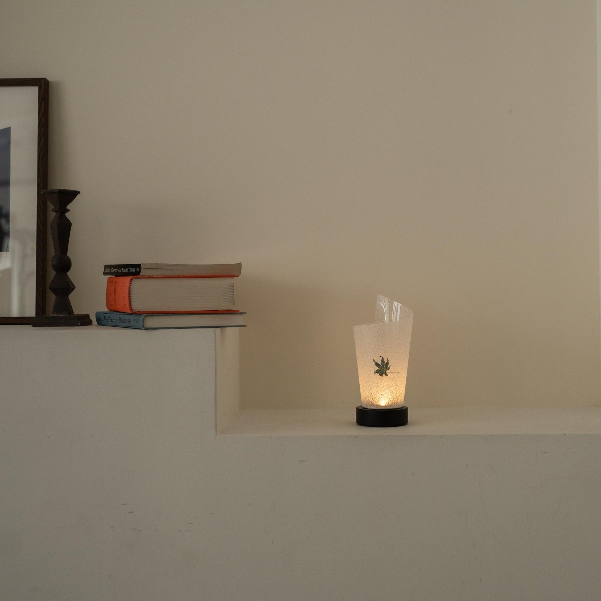 "Lampe de table japonaise en papier « Maki » avec feuille d'érable Momiji, éclairant chaleureusement comme une lampe d'ambiance sur une console blanche dans un salon Japandi."