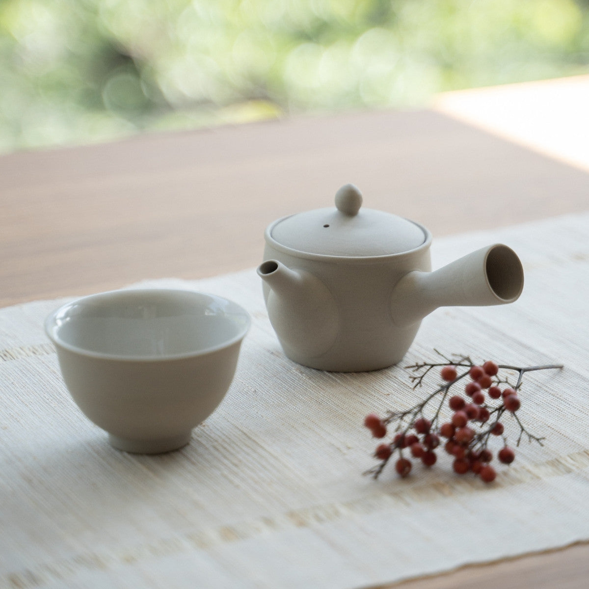 White Japanese teapot "Fuyo" and a Japanese tea cup on a linen mat for tea lovers preparing a tranquil daily ritual.