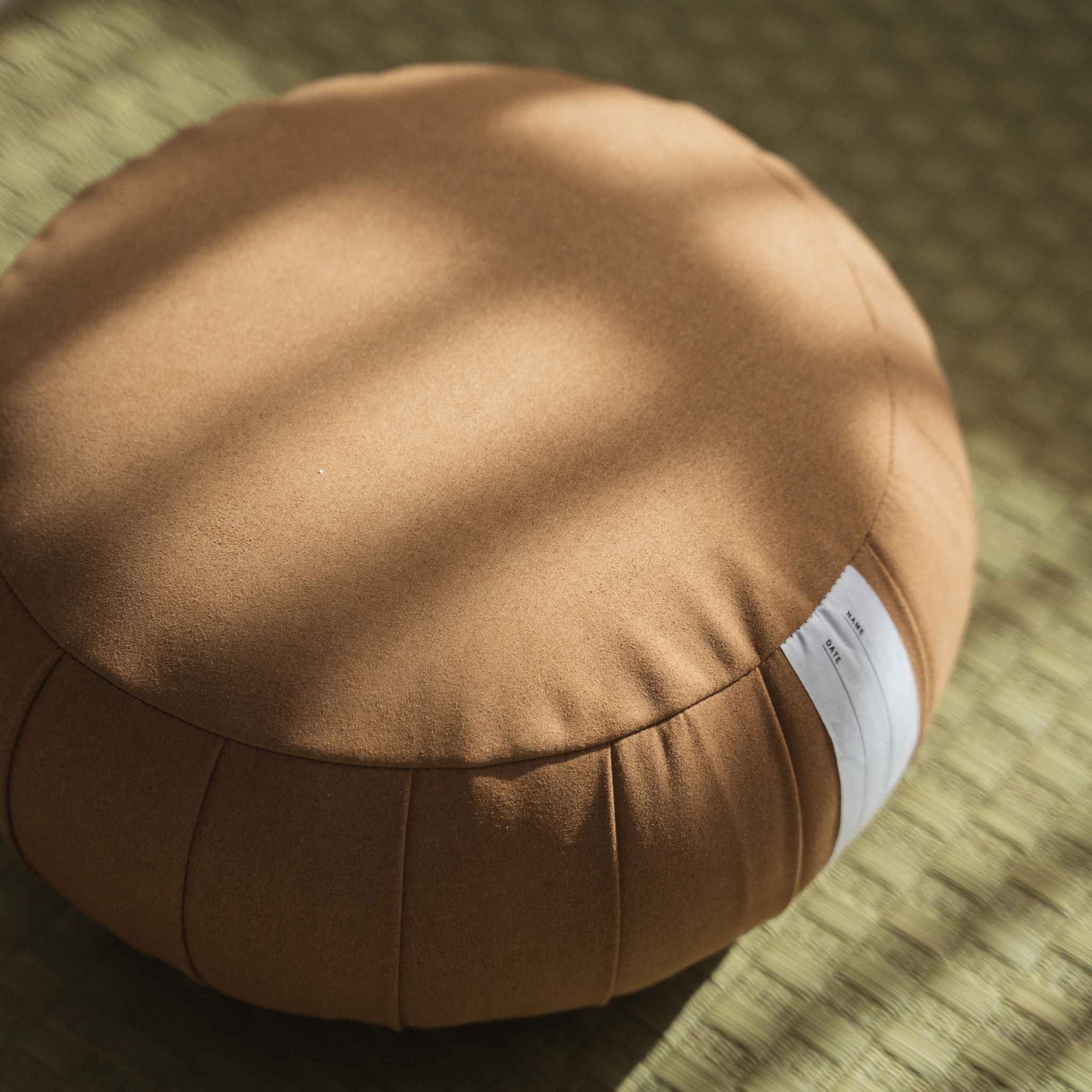 Tæt på detalje af karamelbrun zafu meditationspude, der viser skridsikkert ruskindslignende stoftekstur på tatami.