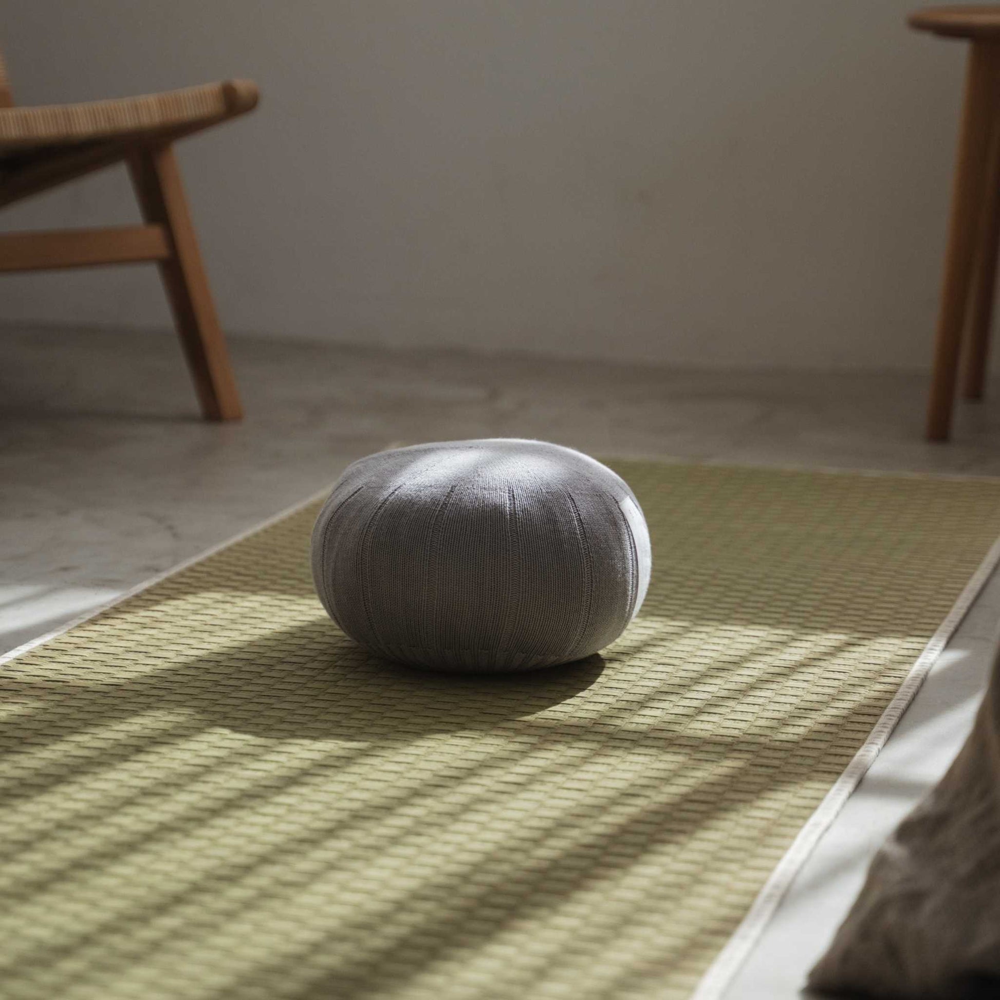 Lagoon grå zafu meditationspude placeret på en tatami-måtte oplyst af naturligt vindueslys.