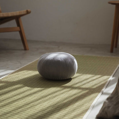 Lagoon grå zafu meditationspude placeret på en tatami-måtte oplyst af naturligt vindueslys.