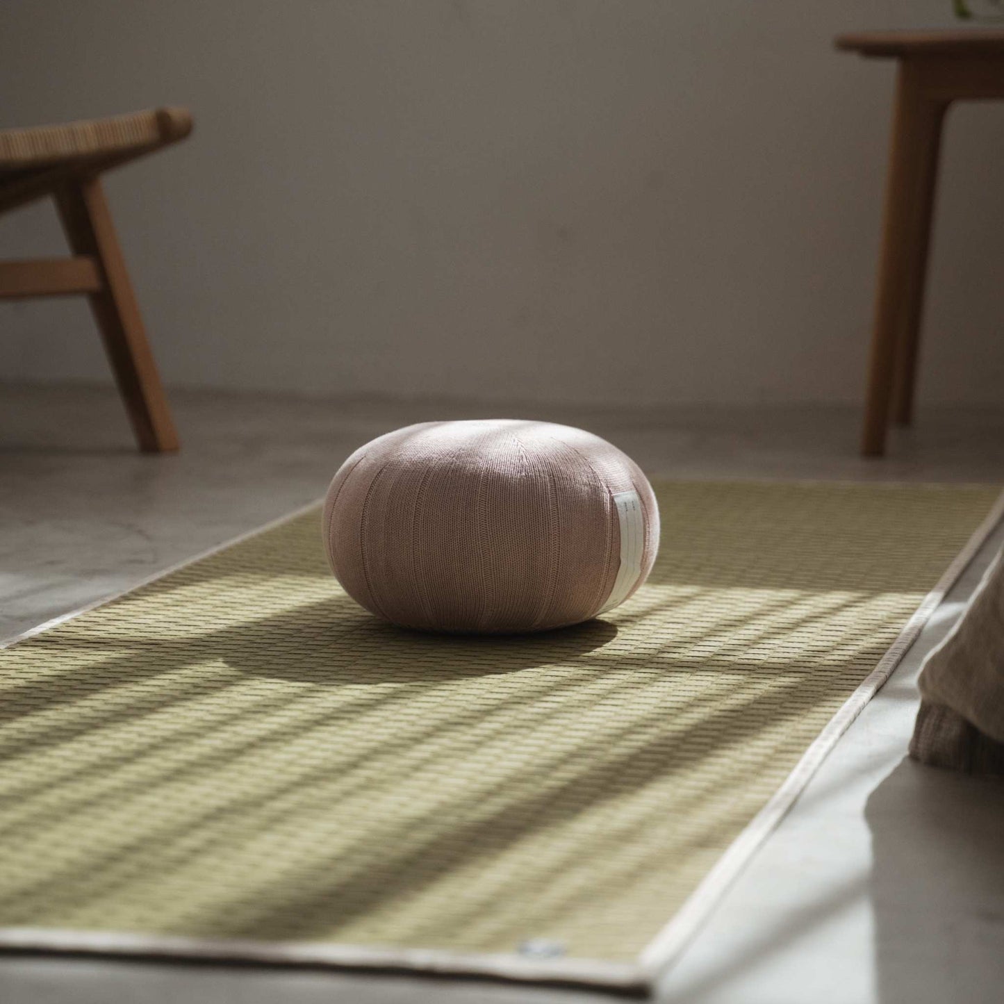 Coussin de méditation zafu japonais rose brumeux assis sur un tapis tatami créant une atmosphère calme pour la pleine conscience.